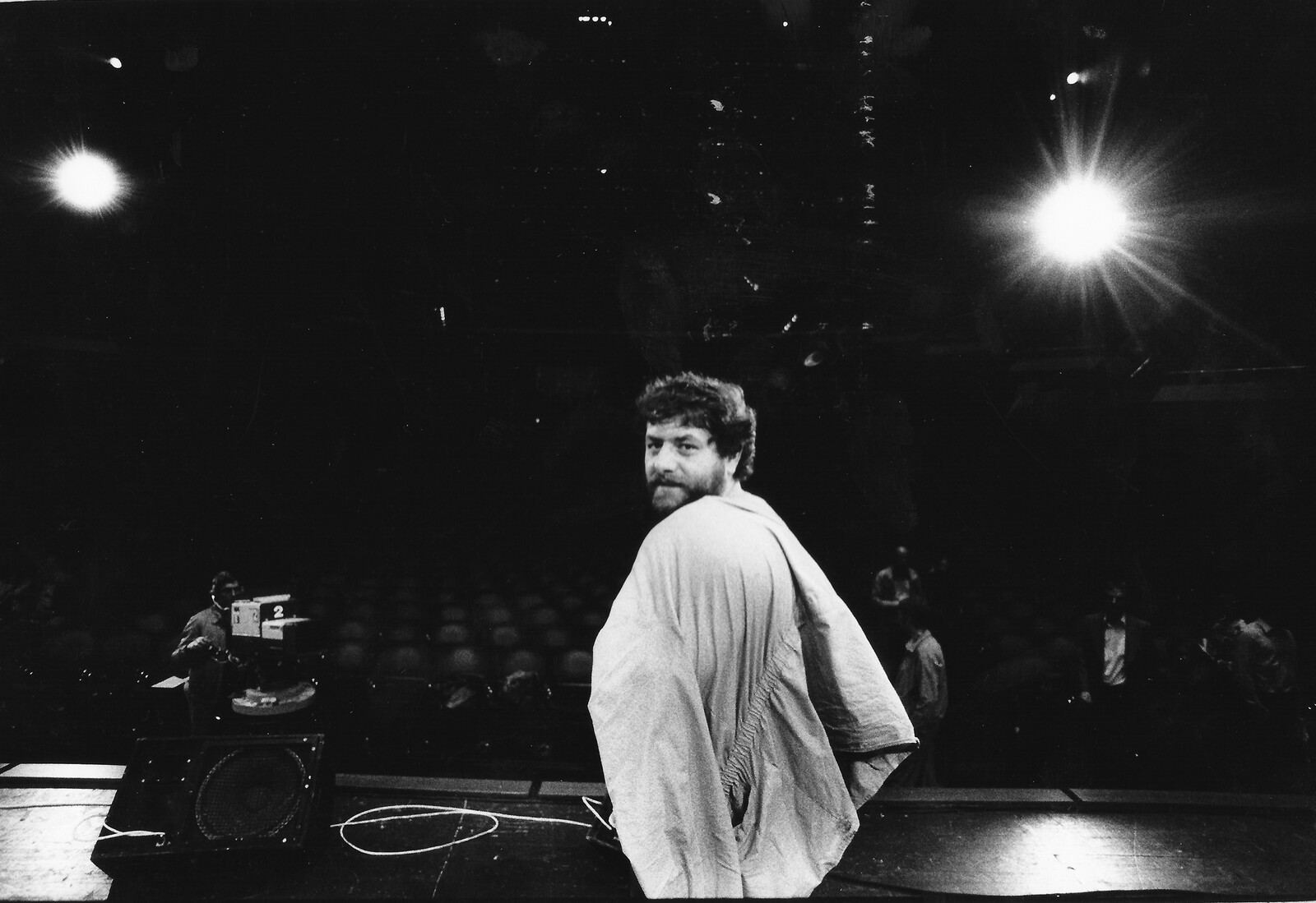 Schwarzweißfoto von der Bühne aus: Harry Pepl blickt über die Schulter in die Kamera, dahinter ein leerer Saal, eine Fernsehkamera und Scheinwerfer.