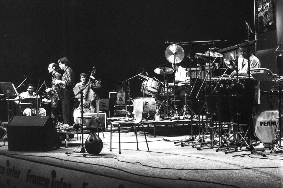 Die ganze Bühne beim Jazzfestival Amiens, Frankreich, Mai 1987: links Harry Pepl, zwei Saxophone und Kontrabass, rechts Schlagzeug und Percussion, vorn ein Banner von France Inter. Von links nach rechts: Harry Pepl, Dave Liebman, Michel Portal, Jean-François Jenny-Clark am Kontrabass, Jack DeJohnette am Schlagzeug und Mino Cinelu an der Percussion. Die Namen nannte der Fotograf Frank Lantiez; sie stimmen mit der Besetzung von „Men's Land“ überein, dem Livealbum vom selben Festival.